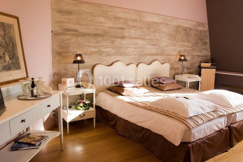 Chambre lumineuse avec lit double, tables de chevet, bureau et décoration murale en bois clair.