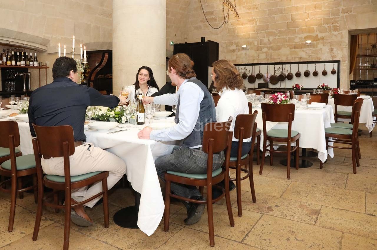 Des personnes trinquent autour d'une table dans une salle de restaurant élégante avec des murs en pierre.