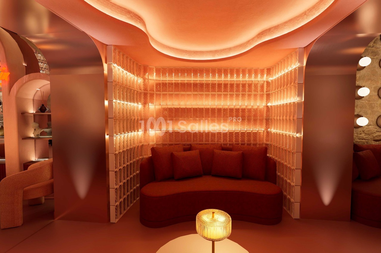Espace lounge avec banquette incurvée, éclairage tamisé et murs texturés dans des tons chauds.