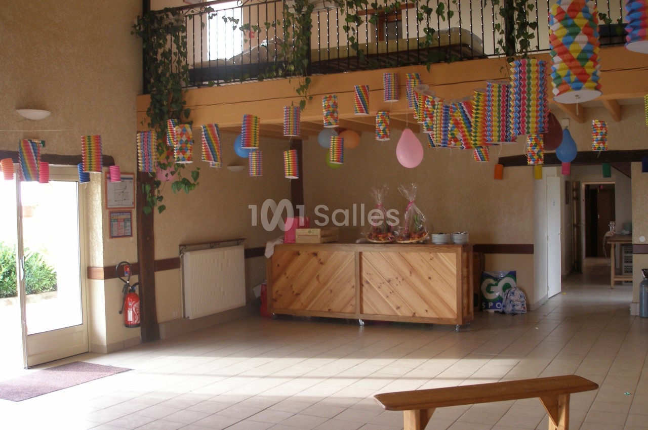 Salle décorée avec des lanternes colorées suspendues, un banc en bois au premier plan et un comptoir en arrière-plan.