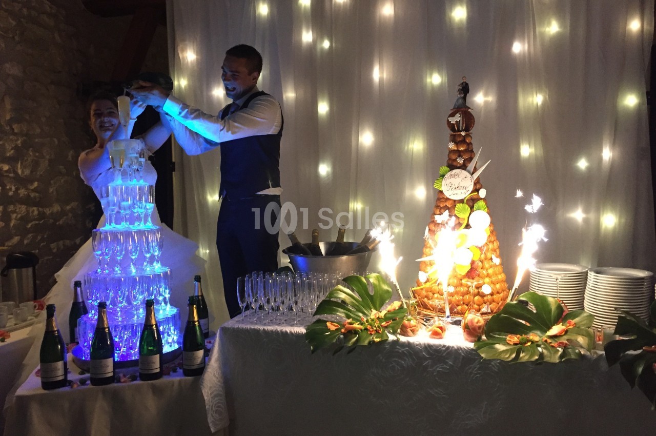 Un couple célèbre son mariage avec une fontaine de champagne illuminée et une pièce montée décorée.