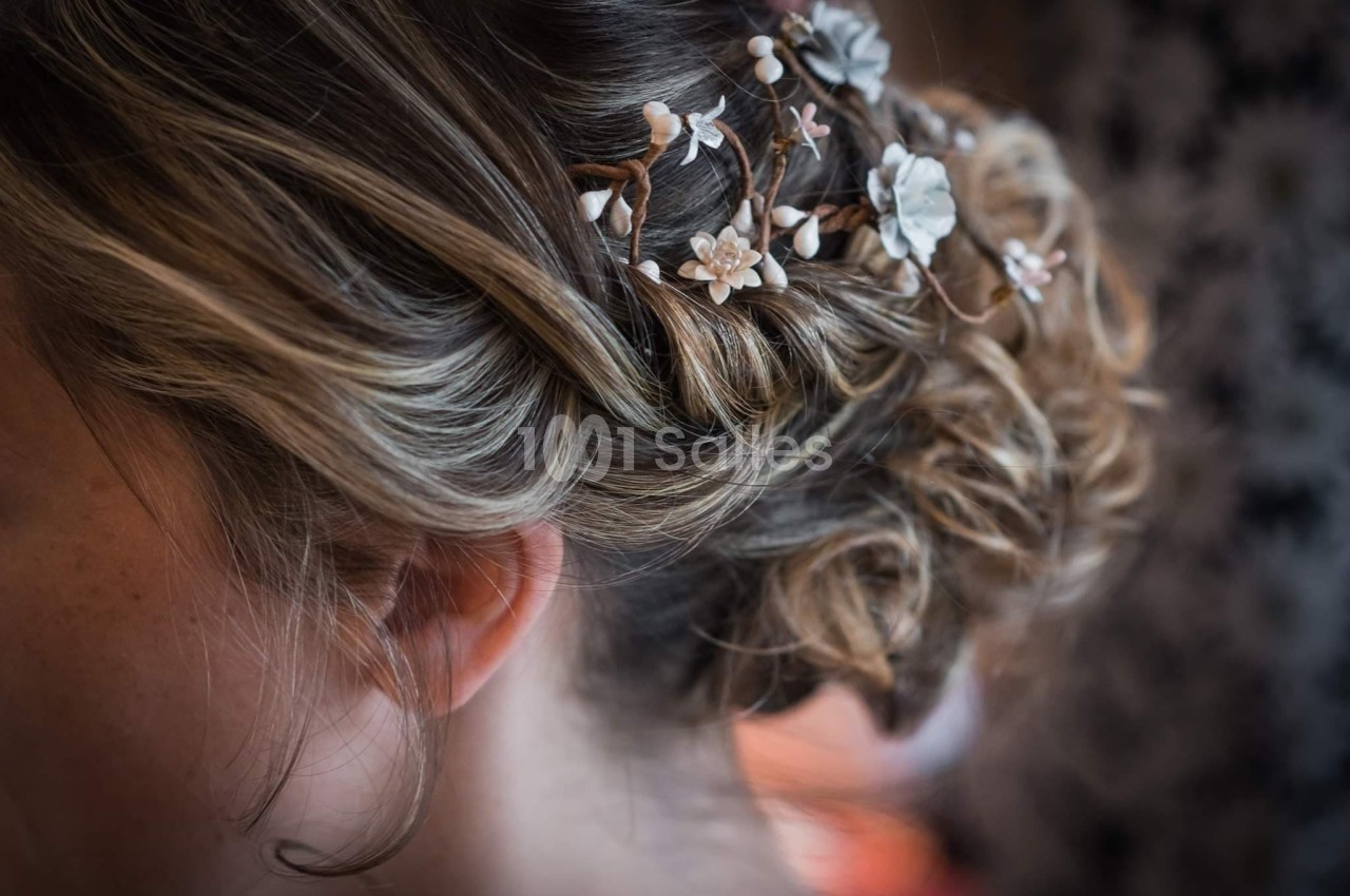Cheveux blonds coiffés en chignon avec des ornements floraux délicats.