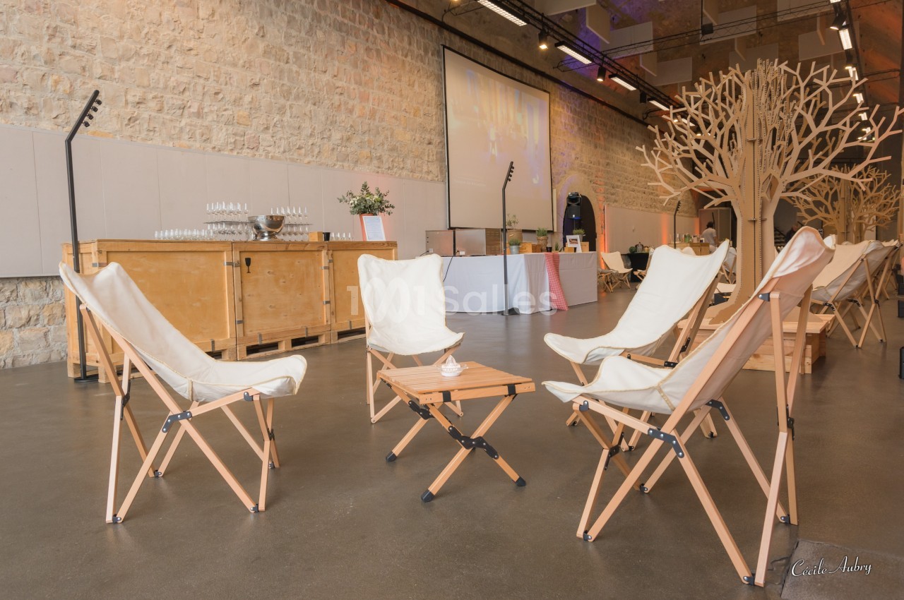 Chaises pliantes en toile blanche disposées autour d'une table basse en bois dans une salle avec murs en pierre.