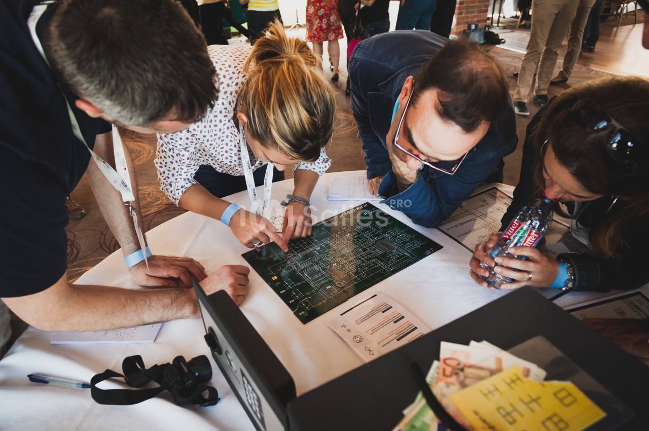 Des personnes collaborent autour d'une table, examinant un plan ou un schéma électronique.