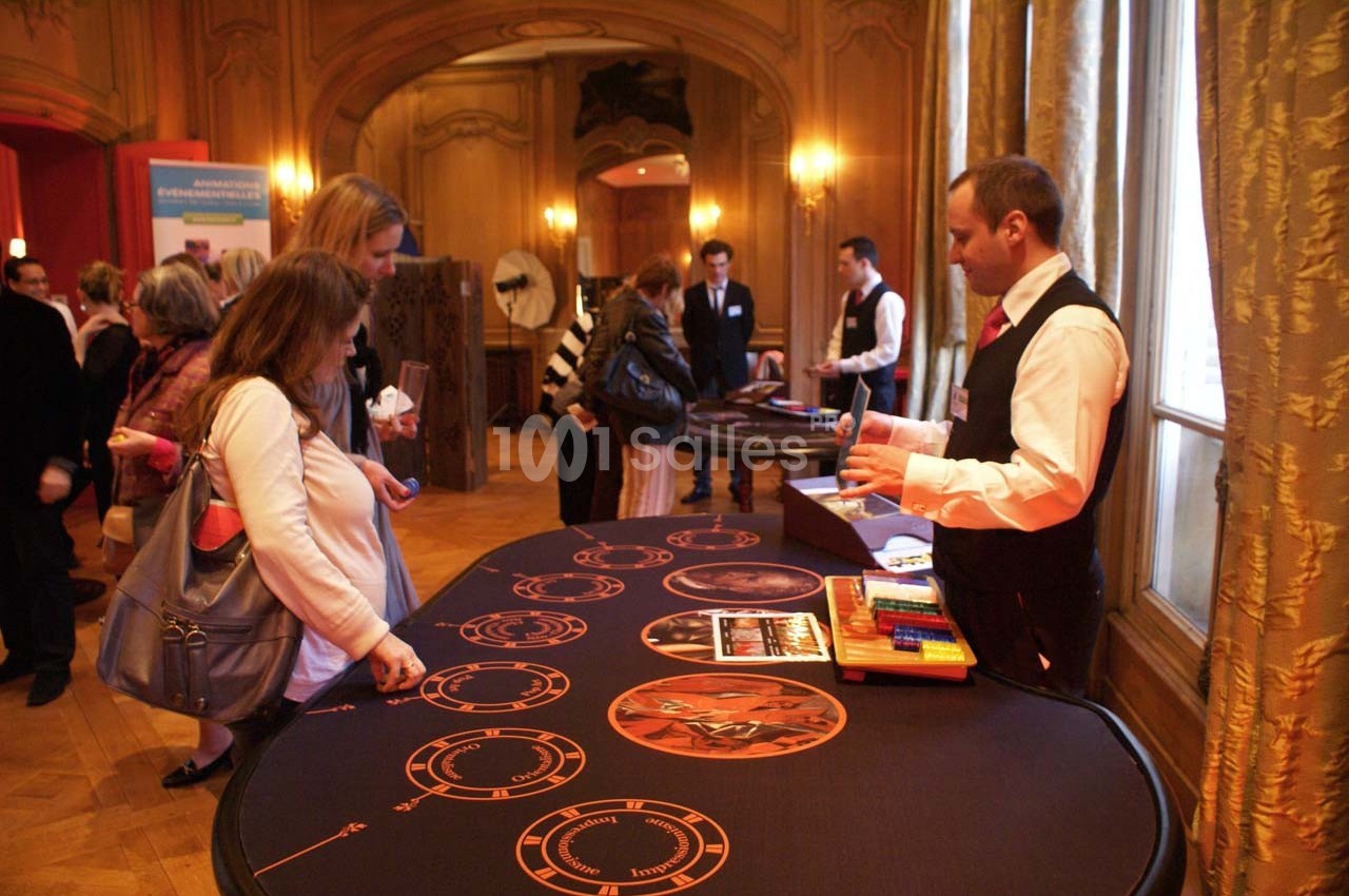 Des personnes se tiennent devant une table de jeu animée par un croupier dans un espace intérieur élégant.