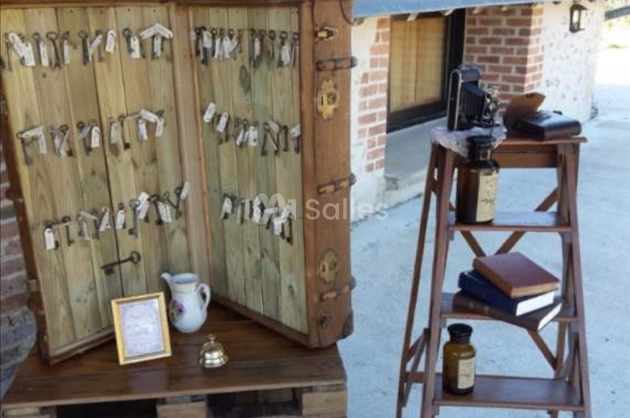 Armoire en bois ouverte avec des clés suspendues, à côté d'une échelle portant des livres et des objets anciens.