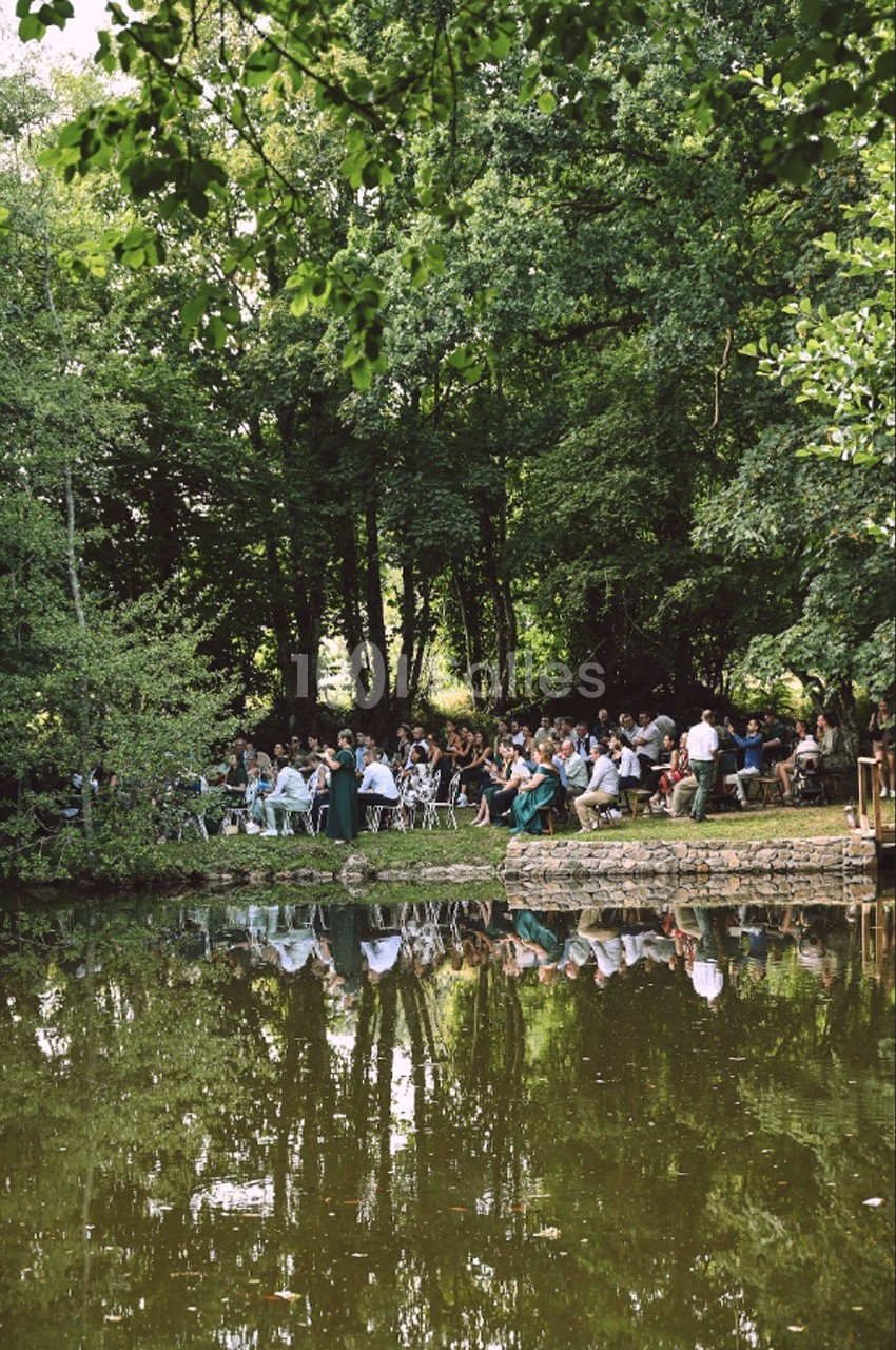 Un groupe de personnes assises en plein air près d'un étang entouré d'arbres.