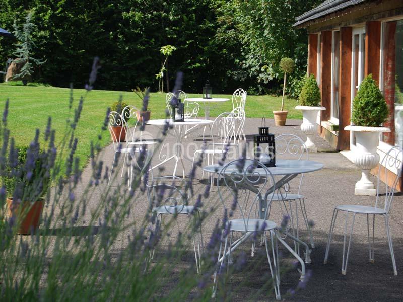 Mobilier de jardin en fer forgé blanc disposé sur une terrasse, entouré de verdure et de lavande.