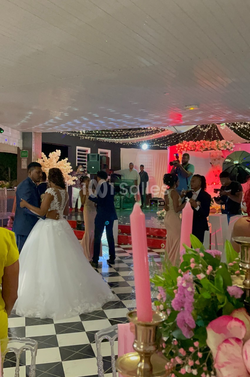 Des couples dansent lors d'une réception de mariage sous une tente décorée de lumières et de fleurs.