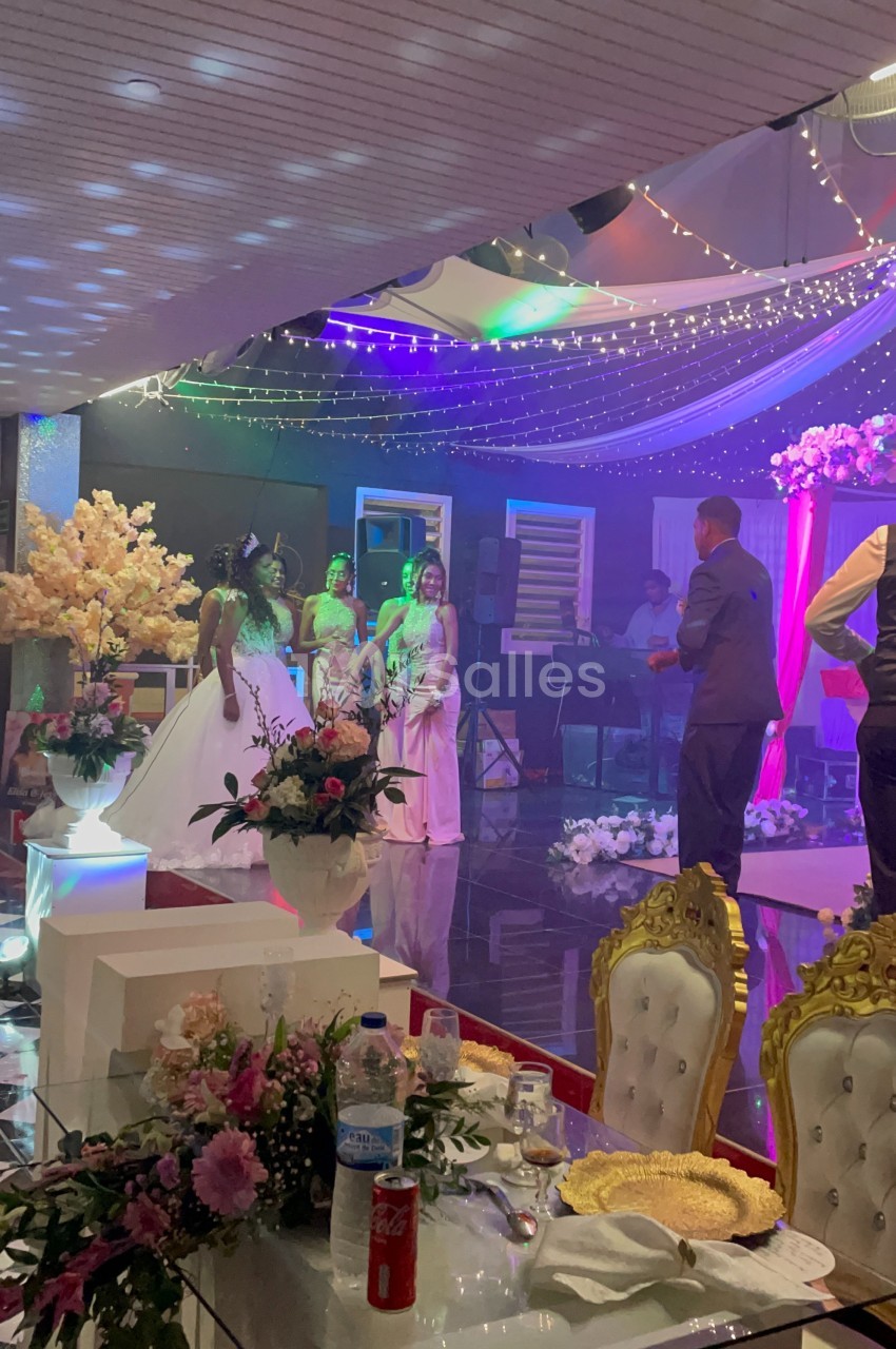 Des personnes en tenue de soirée discutent sur une piste de danse décorée avec des lumières et des fleurs.