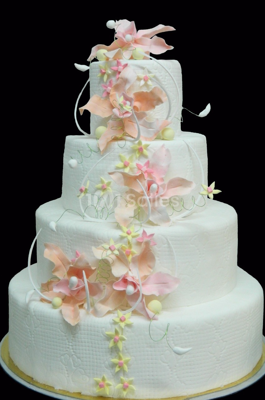 Gâteau de mariage à quatre étages décoré de fleurs en sucre roses et blanches avec des détails délicats.