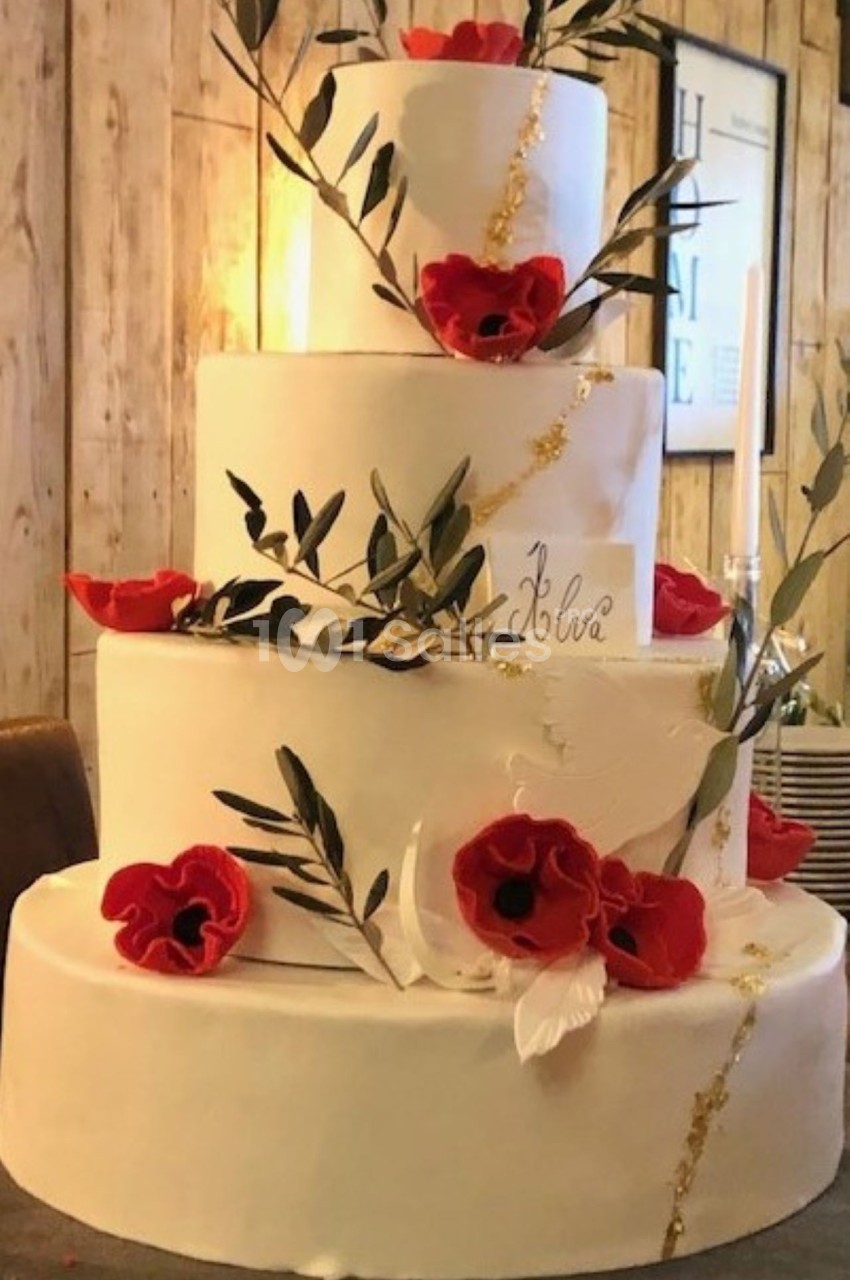 Gâteau de mariage à trois étages décoré de coquelicots rouges, de feuillage et de détails dorés.
