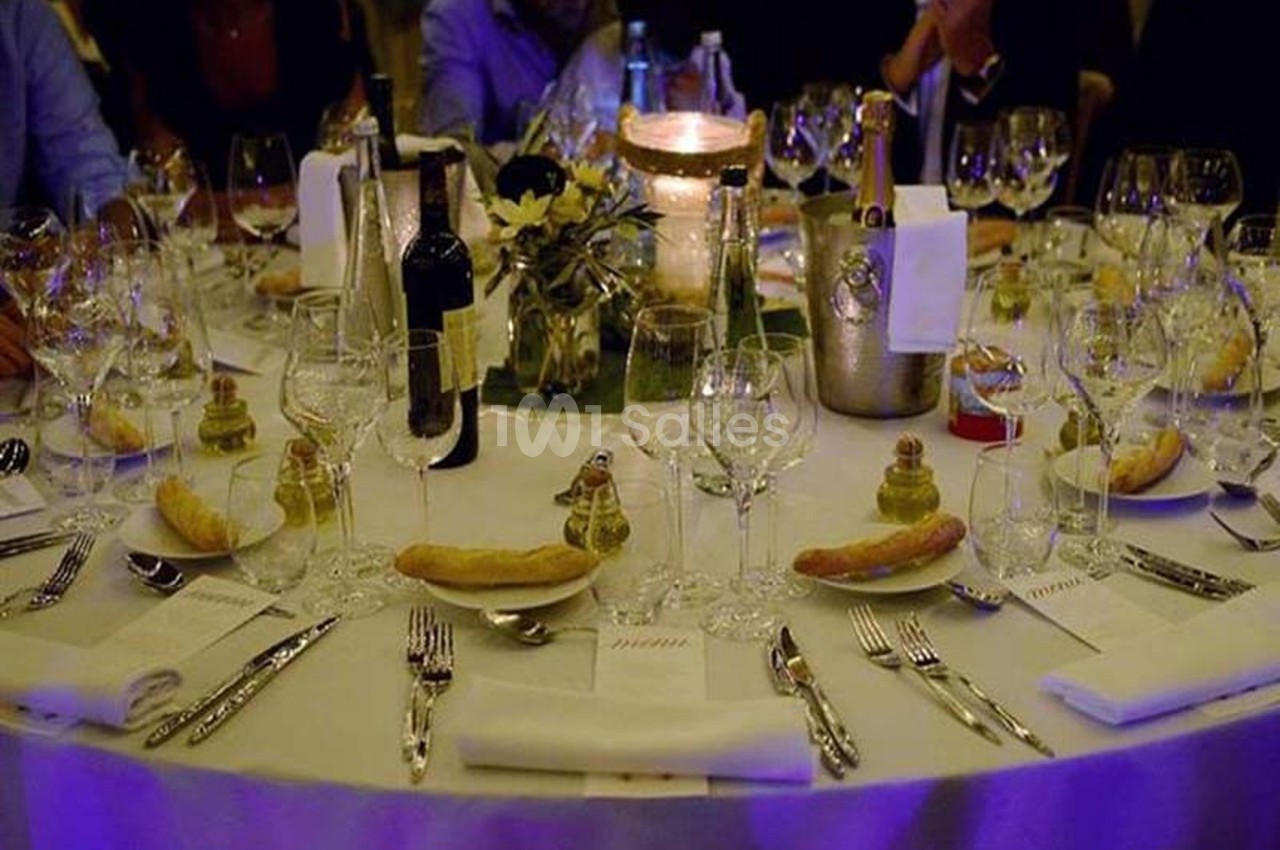 Table dressée pour un dîner élégant avec verres, assiettes, couverts, bougies et décorations florales.