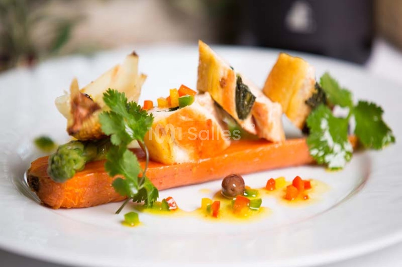 Assiette de légumes colorés avec carotte entière, asperge, morceaux de légumes grillés et herbes fraîches.