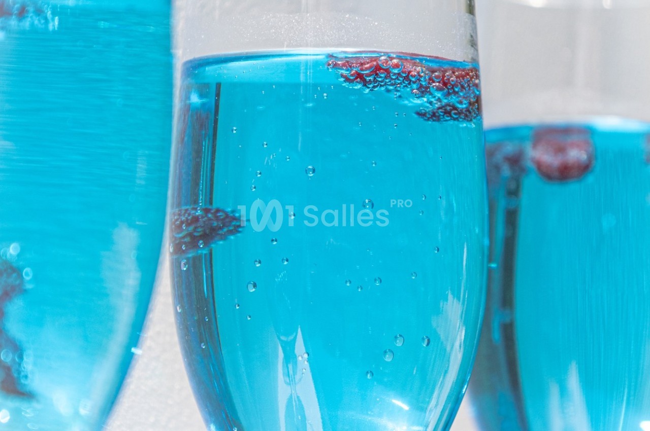 Verres remplis de liquide bleu pétillant avec des baies rouges flottant à la surface.