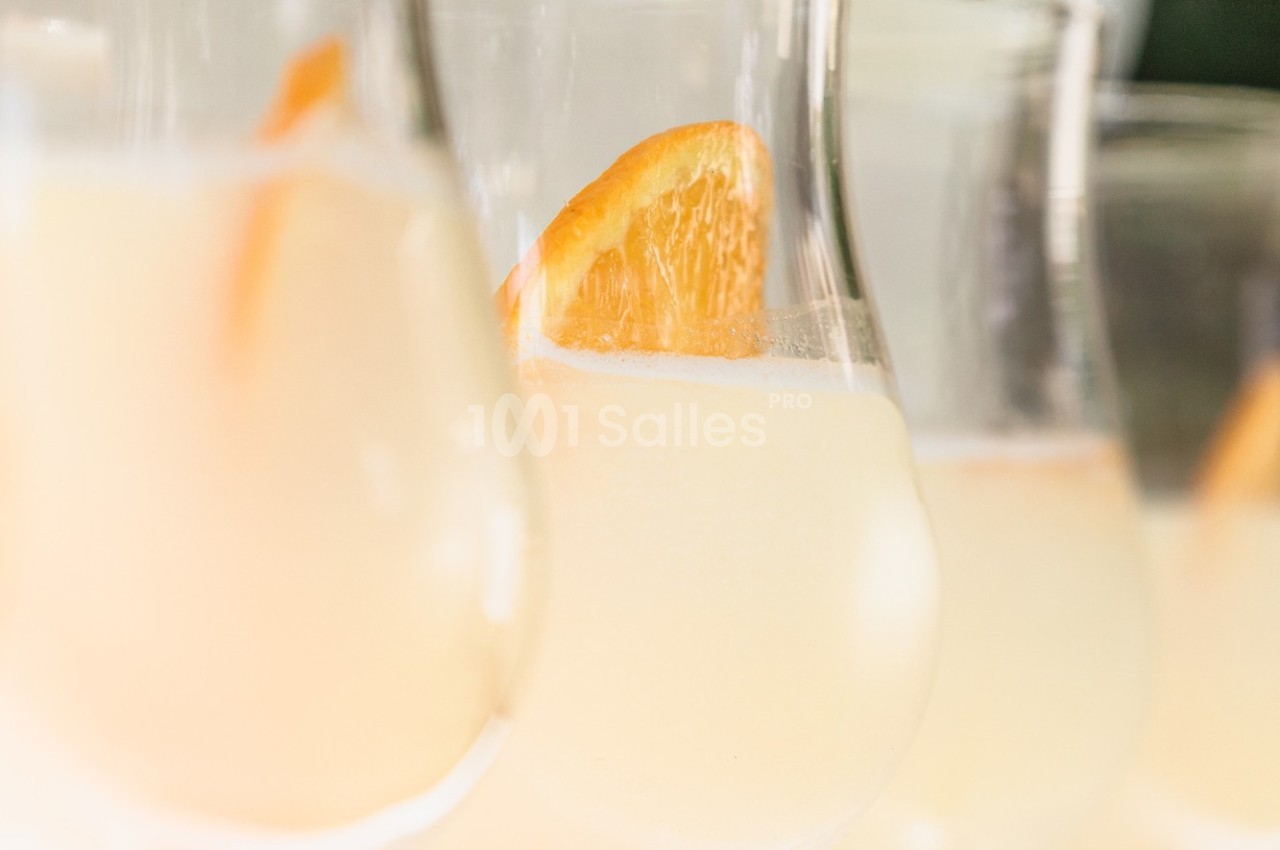 Verres de cocktail clair garnis de tranches d'orange, photographiés en gros plan avec une lumière douce.