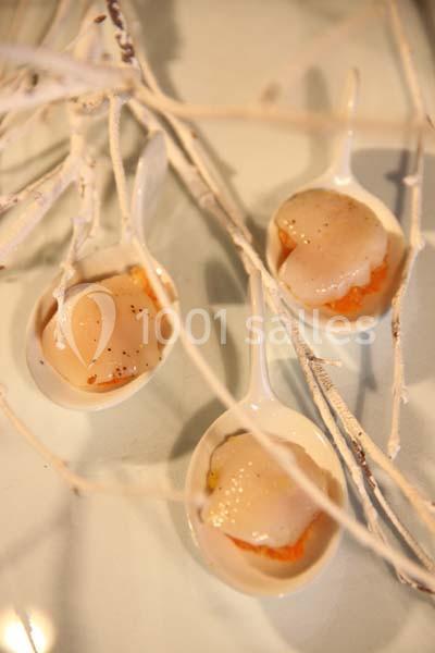 Trois cuillères contenant des noix de Saint-Jacques sur une purée, décorées de branches blanches.
