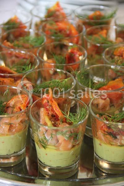 Verrines garnies de mousse verte, saumon fumé, tomates et brins d'aneth, présentées sur un plateau.