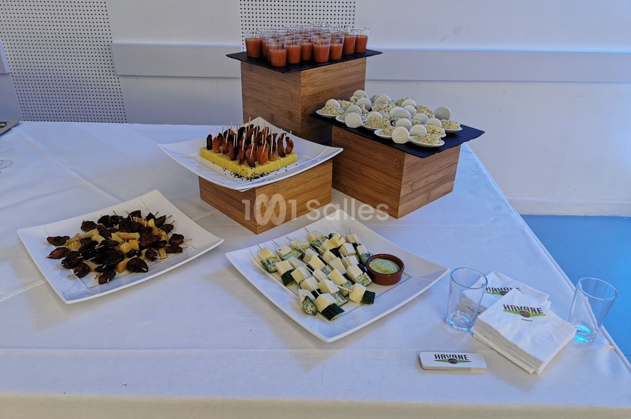 Plateau de buffet avec verrines, amuse-bouches variés et serviettes disposés sur une nappe blanche.
