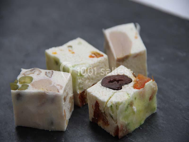 Quatre morceaux de nougat aux fruits secs et confits, disposés sur une surface sombre.