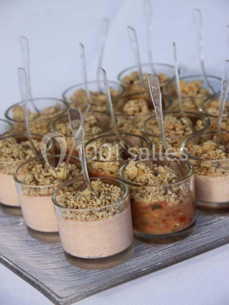 Verrines individuelles garnies de mousse salée et crumble, présentées sur un plateau avec des cuillères transparentes.