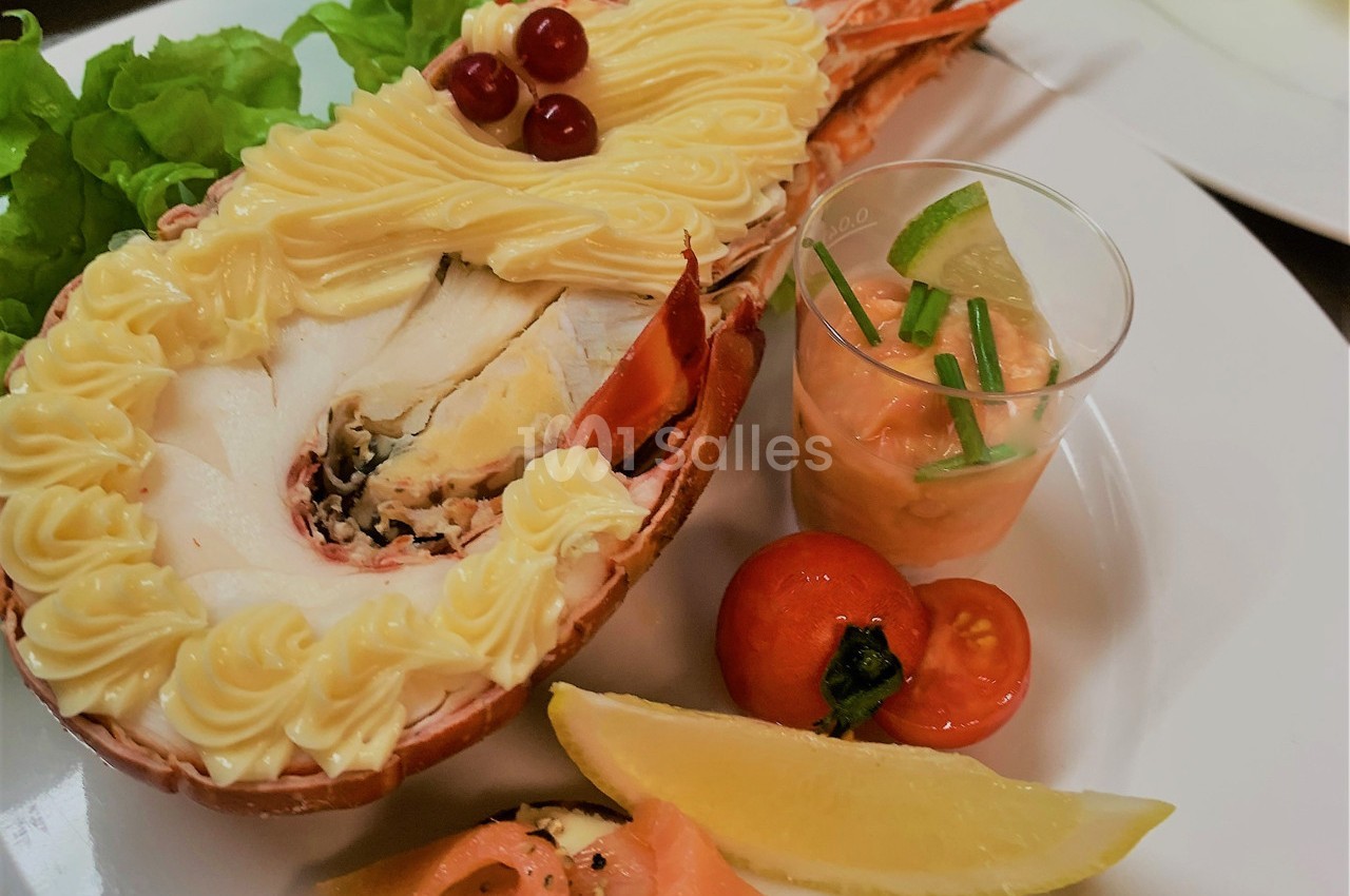 Homard garni de mayonnaise, accompagné de salade, citron, tomate cerise et verrine de sauce rose.