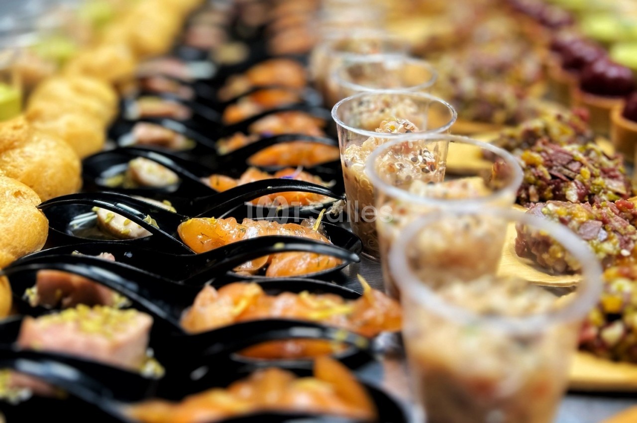 Assortiment de bouchées apéritives variées disposées sur une table, comprenant verrines, poissons et autres mets.