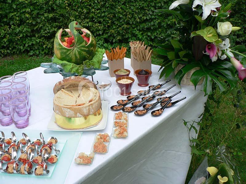 Table dressée en extérieur avec des amuse-bouches, pains, sauces, et une décoration de pastèque sculptée.
