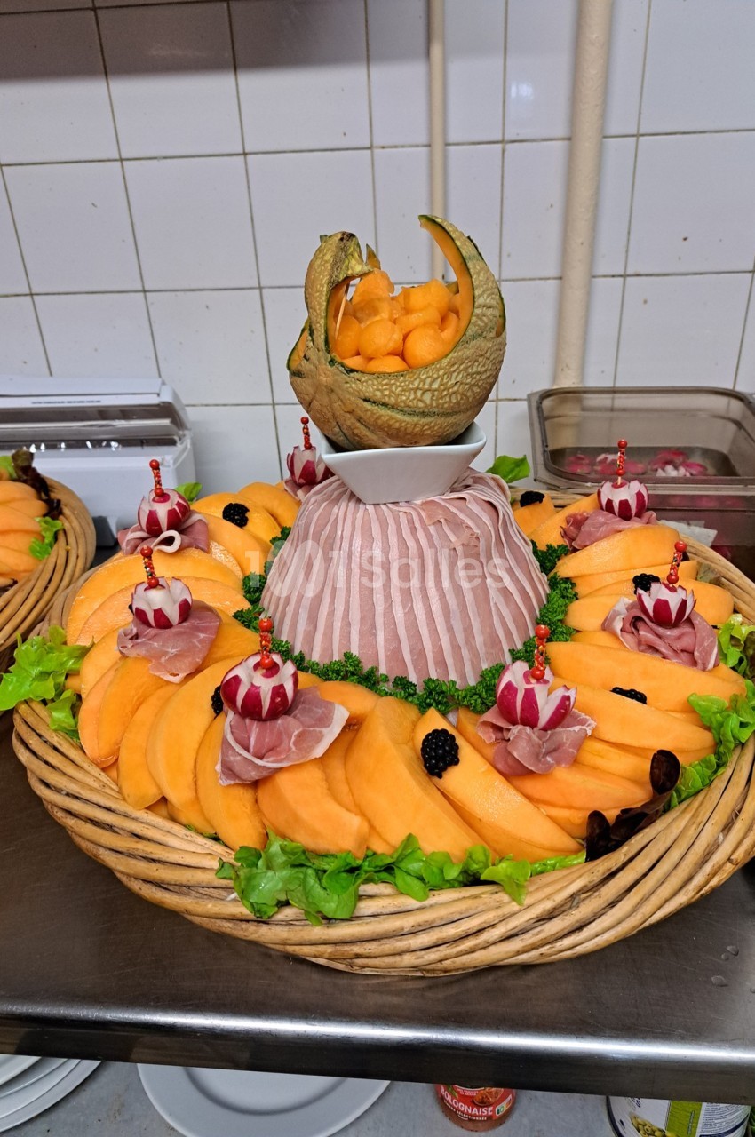 Plateau de présentation avec tranches de melon, jambon cru, décorations de radis et boulettes de melon dans une coque.