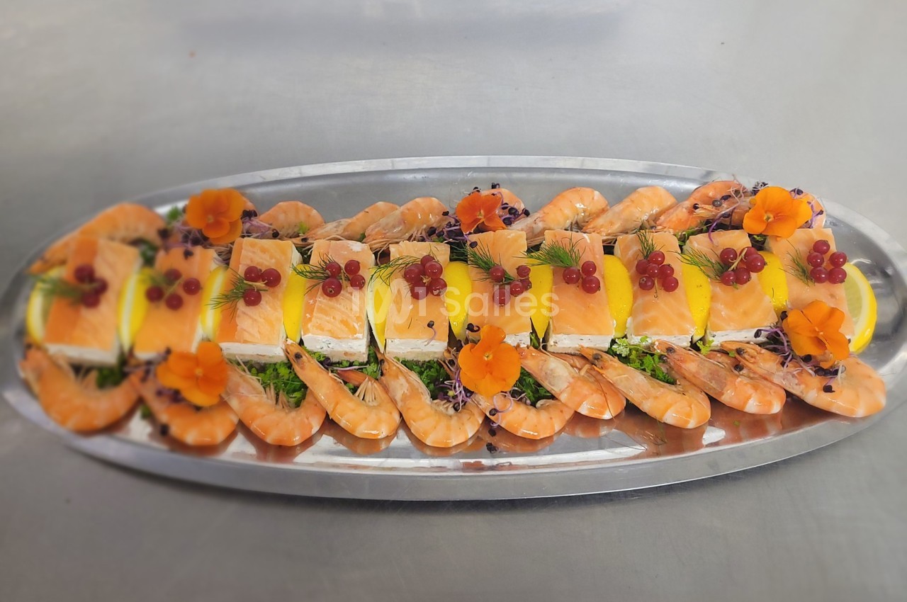 Plateau de fruits de mer avec crevettes, tranches de saumon, citron, groseilles et décorations florales sur un lit de…