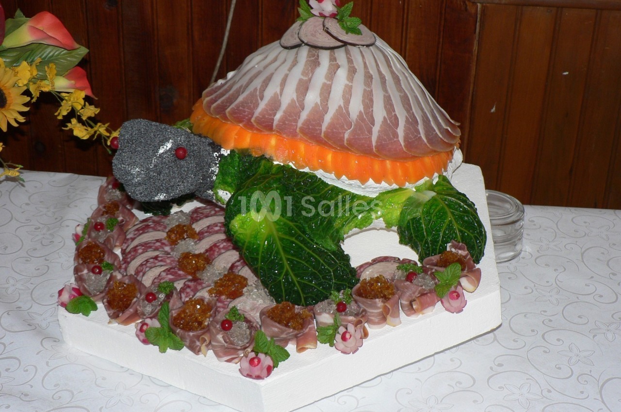Représentation culinaire d'une tortue composée de légumes, charcuterie et garnitures sur un plateau décoratif.