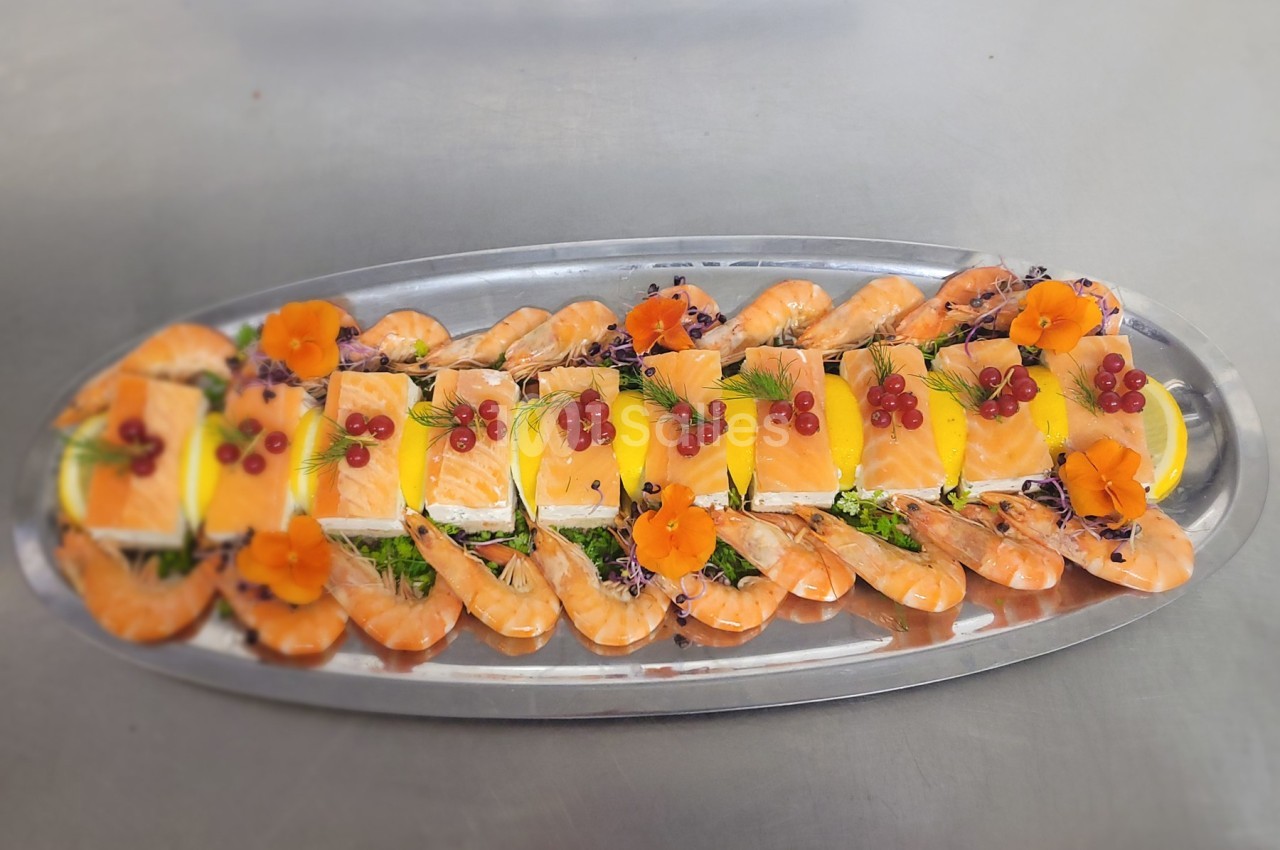 Plateau de fruits de mer avec crevettes, tranches de saumon, citron, herbes fraîches et décorations florales.