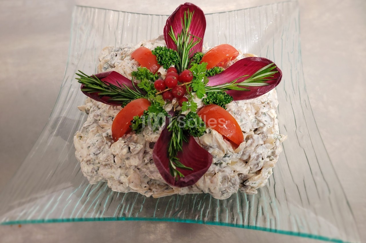 Salade composée crémeuse garnie de tomates, feuilles de radicchio, herbes fraîches et groseilles rouges sur un plat en verre.
