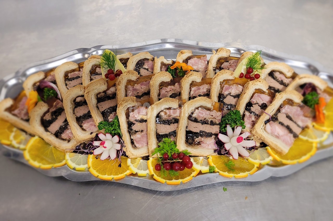 Plateau de pâtés en croûte garnis de tranches d'orange, groseilles et décorations florales en légumes.