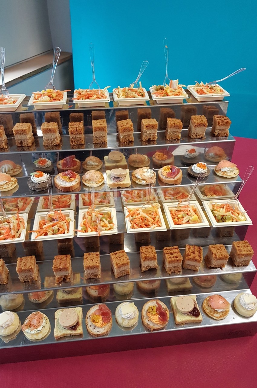 Présentoir à plusieurs niveaux avec divers amuse-bouches, incluant verrines, toasts et bouchées salées.