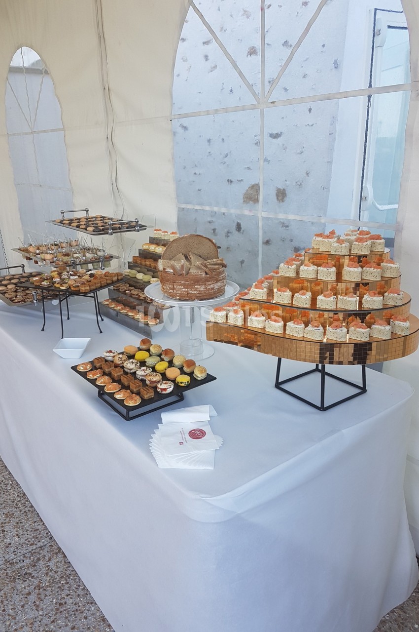 Table garnie de desserts variés, présentés sur des plateaux et supports, dans une tente lumineuse.