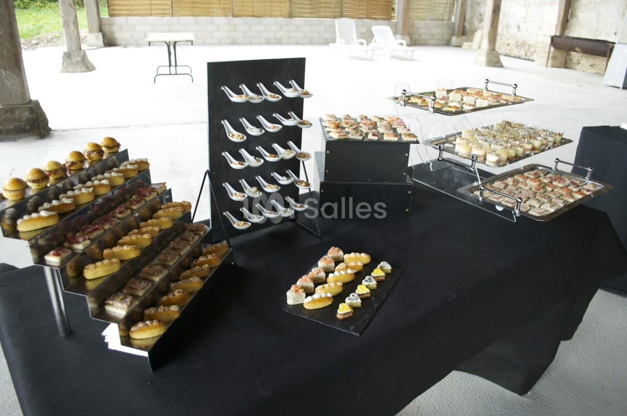 Buffet de petits fours variés disposés sur des présentoirs noirs dans un espace ouvert et lumineux.