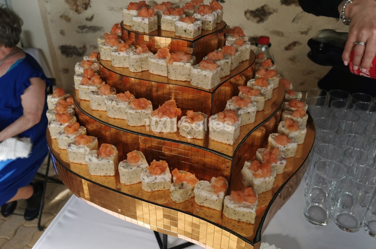 Plateau de pièces montées salées sur plusieurs étages, garnies de mousse et de saumon, présenté sur une table.