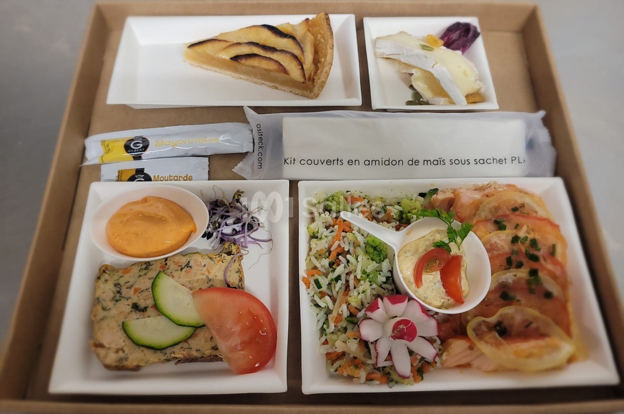 Plateau-repas composé de quiche, crudités, terrine, riz aux légumes, saumon fumé, sauces et couverts biodégradables.