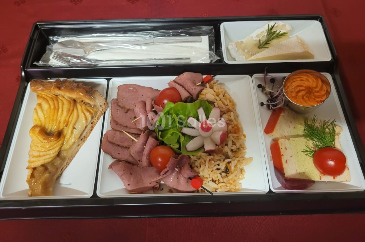 Plateau-repas avec rôti de bœuf, riz, crudités, tarte aux pommes, fromage, mousse et couverts sur nappe rouge.