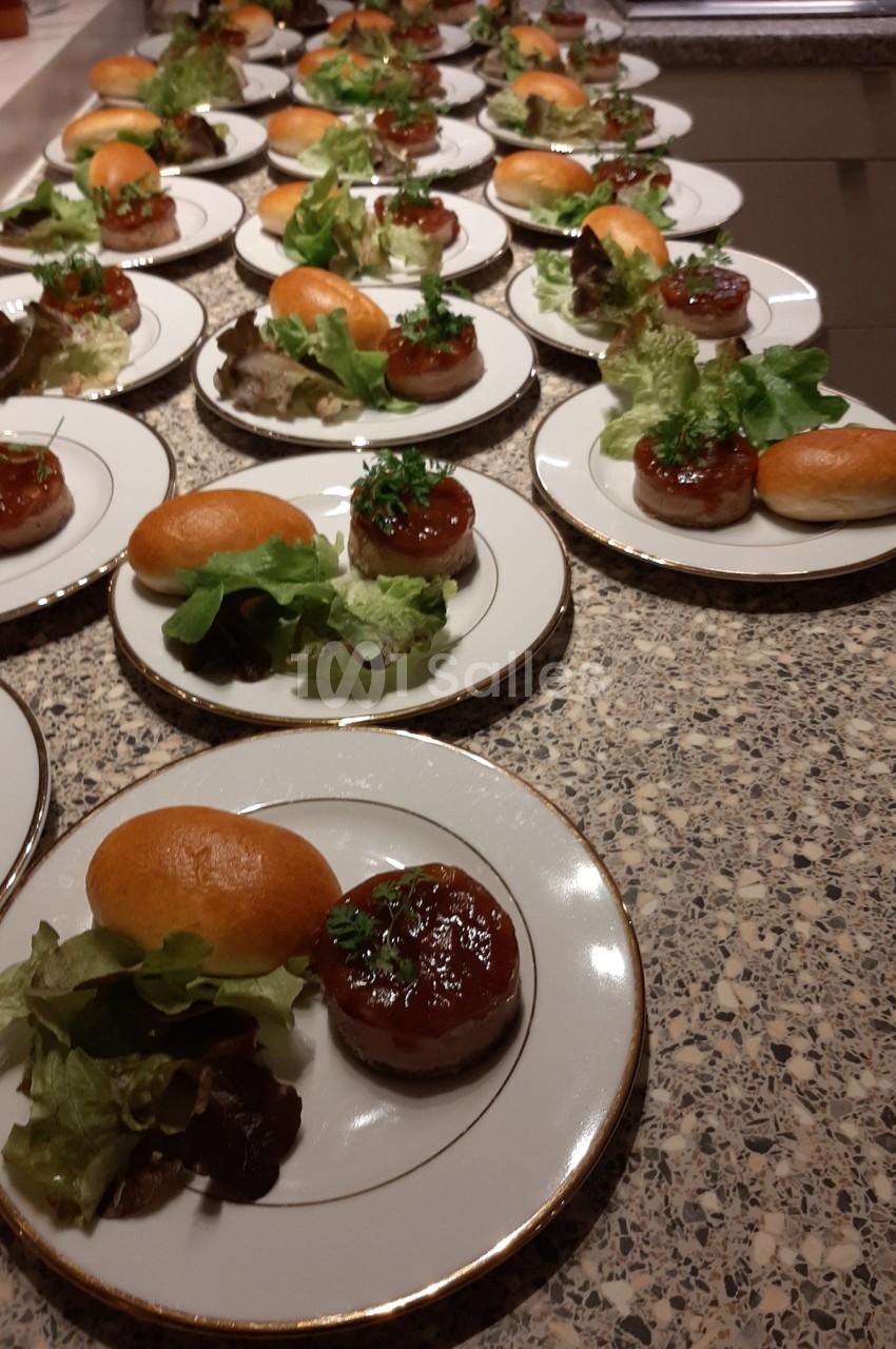 Assiettes alignées contenant des mini-burgers avec salade verte, servies sur un comptoir en granit.
