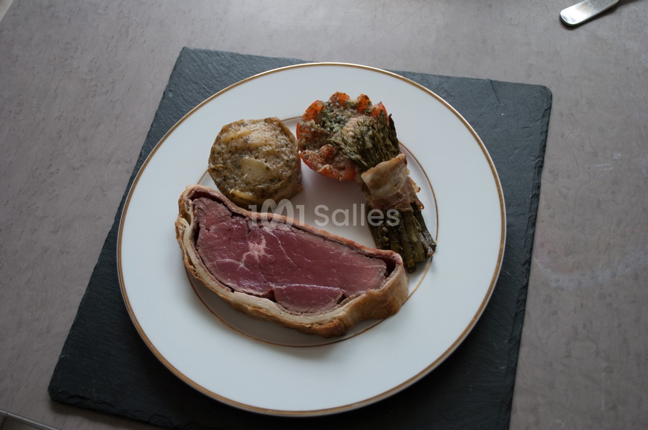 Assiette contenant un filet de viande en croûte, un gratin individuel, des légumes et une garniture d'asperges.