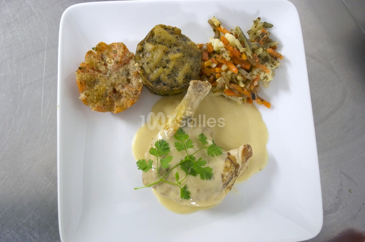 Assiette contenant une cuisse de volaille en sauce, accompagnée de légumes variés et de gratins individuels.