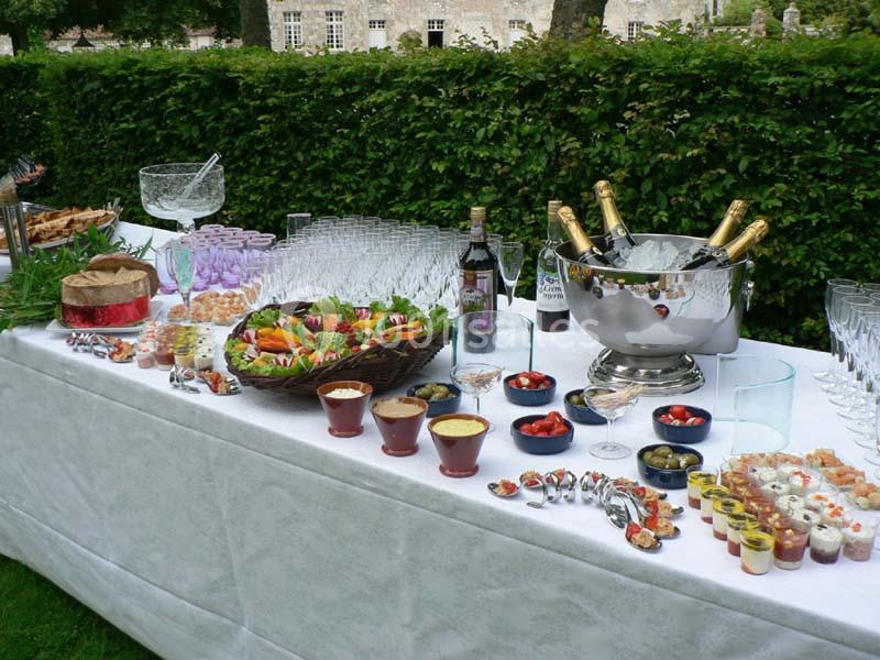 Table dressée en extérieur avec buffet comprenant boissons, coupes de champagne, verrines, fruits et amuse-bouches.