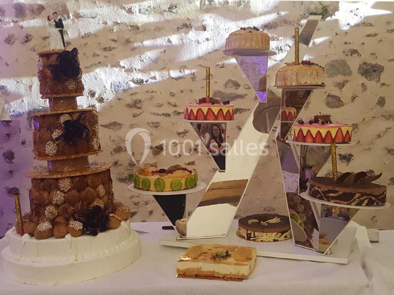 Présentation de plusieurs gâteaux de fête, dont une pièce montée et des pâtisseries variées sur des supports décoratifs.