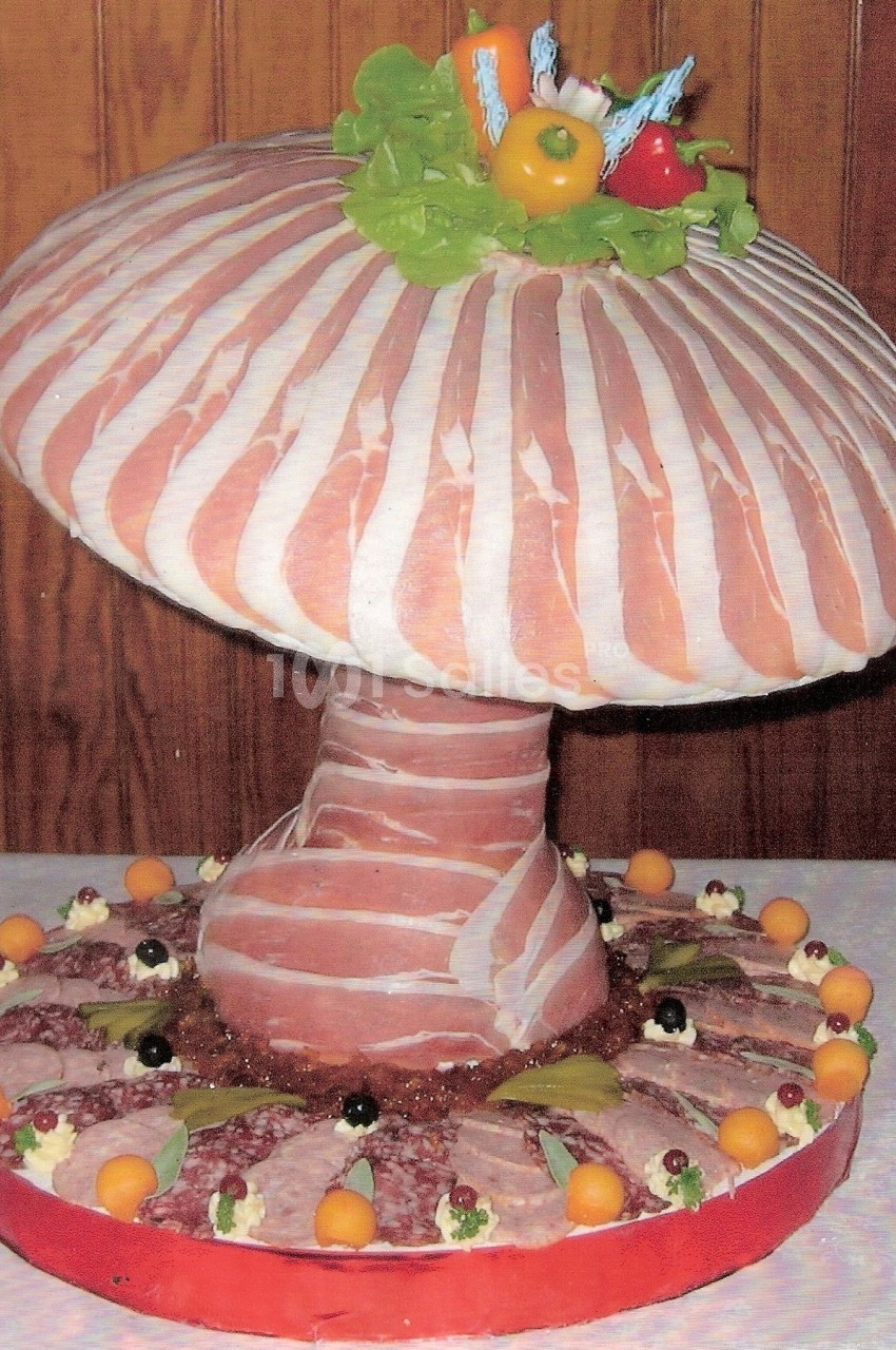 Plateau de charcuterie en forme de champignon, décoré de jambon, légumes et garnitures variées.