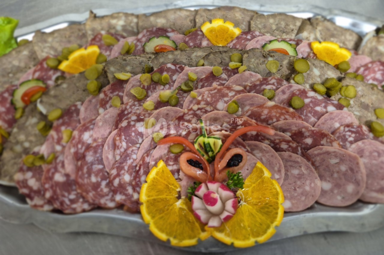 Plateau de charcuterie variée avec tranches de saucisson, pâté et garniture d'oranges, cornichons et légumes.