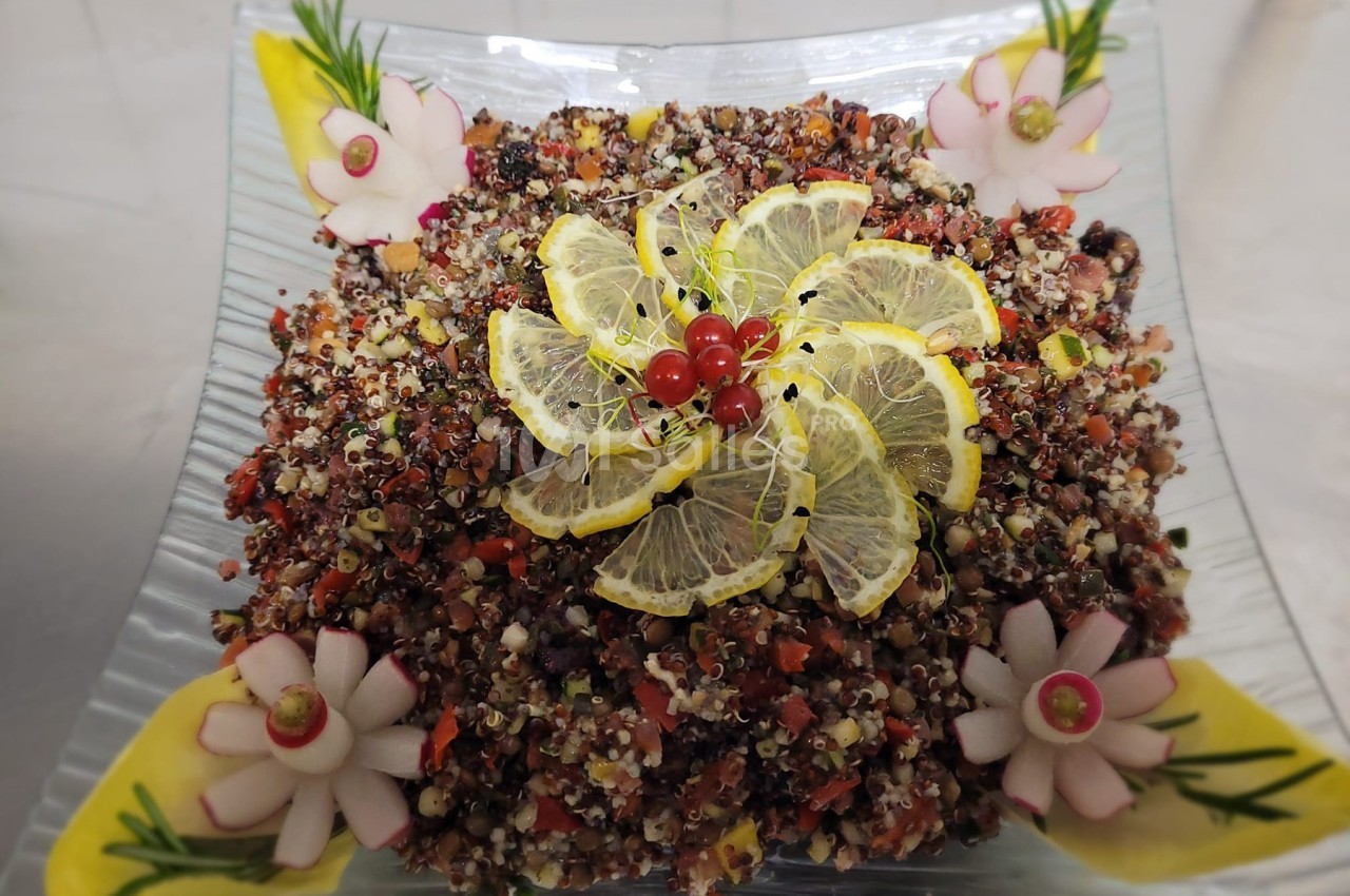 Salade de quinoa colorée garnie de tranches de citron, groseilles rouges et décorations de légumes sculptés.
