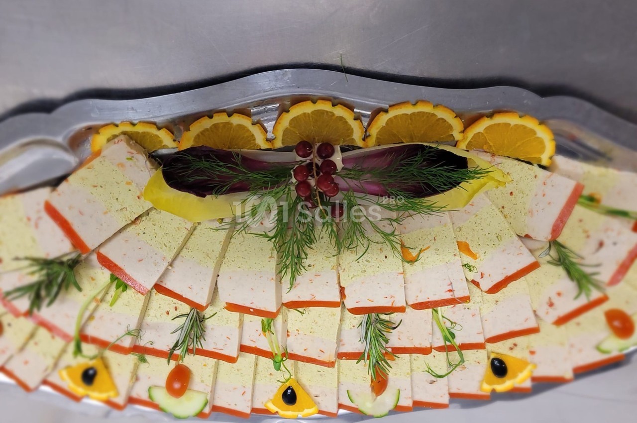 Plateau de tranches de terrine décorées de rondelles d'orange, herbes fraîches et garnitures colorées.