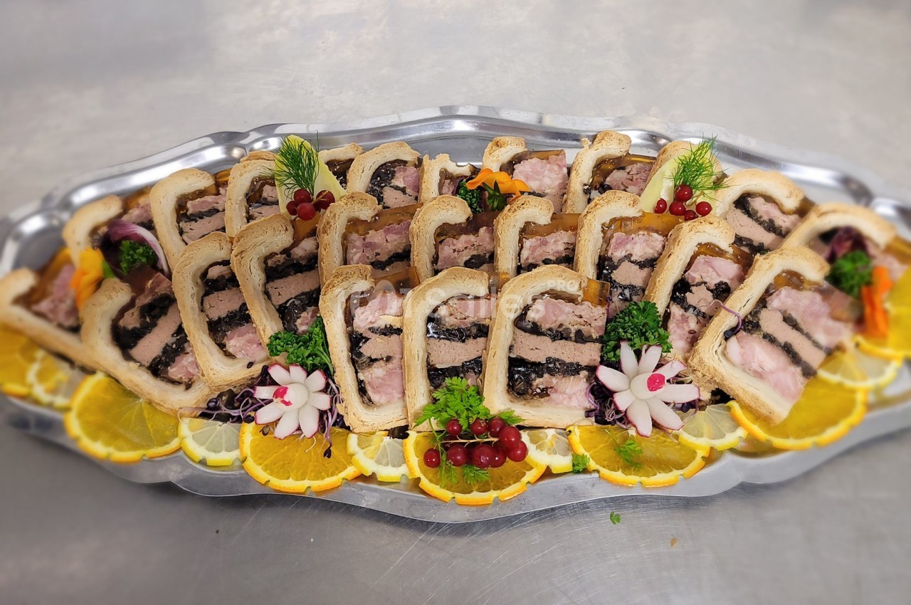 Plateau de pâtés en croûte garnis de tranches d'orange, groseilles et décorations florales en légumes.
